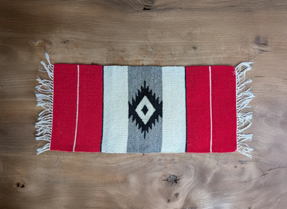 Petit tapis balkanique en laine rouge et gris, tissé à la main. Motif central en losange noir et blanc cassé. Composition simple et traditionnelle.