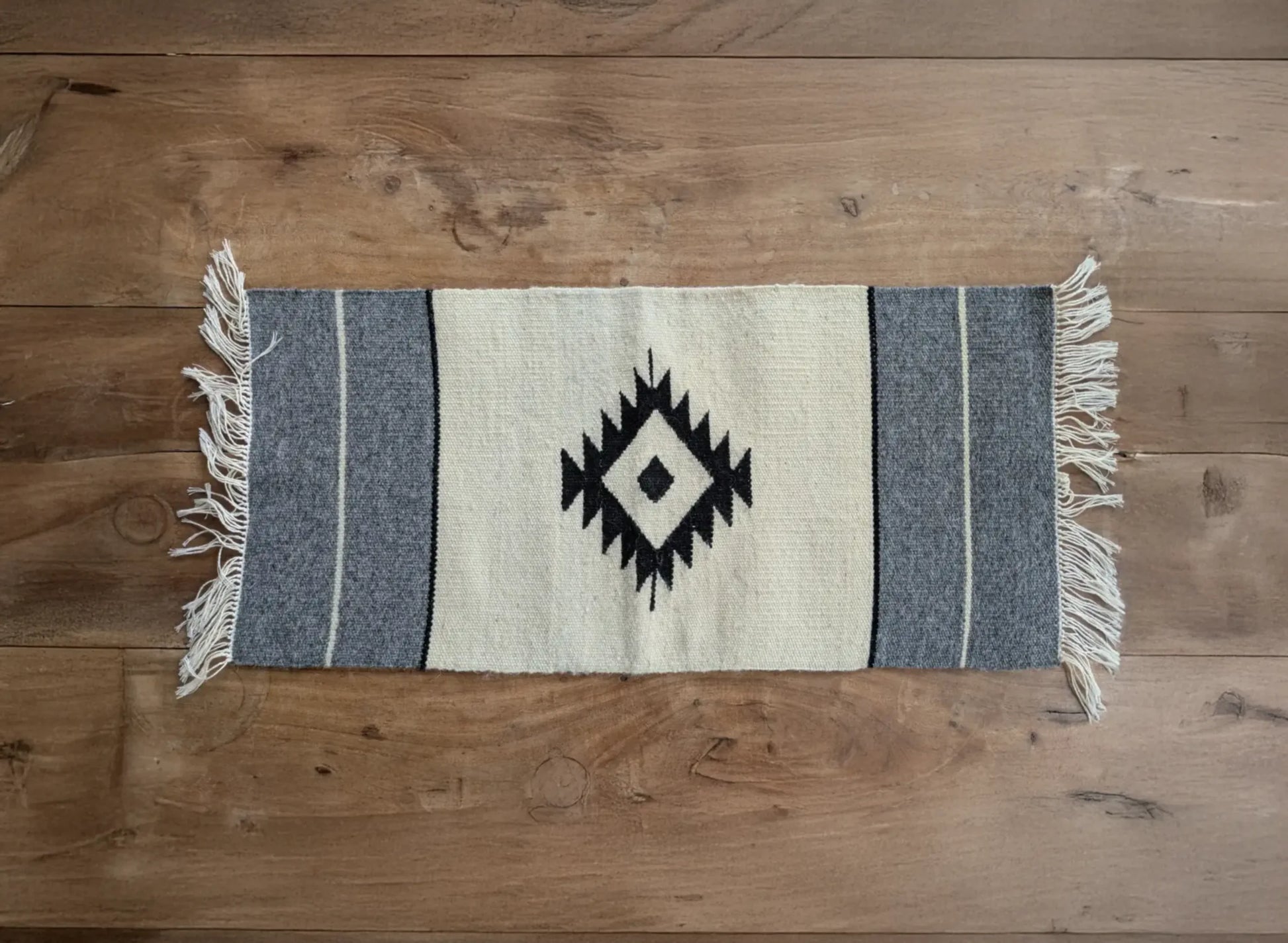 Tapis balkanique en laine tissé main, blanc cassé et gris. Le motif central en losange apporte une touche traditionnelle. Une pièce sobre aux lignes simples.