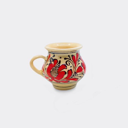 Tasse en céramique de Corund galbée avec décor floral rouge székely sur fond crème émaillé. Faïence artisanale roumaine peinte à la main. Format 15 cl.