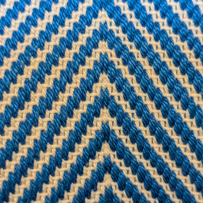 Texture textile artisanale bleue et blanche, tissage sergé à chevrons, contraste délicat des fils, vue rapprochée du motif.