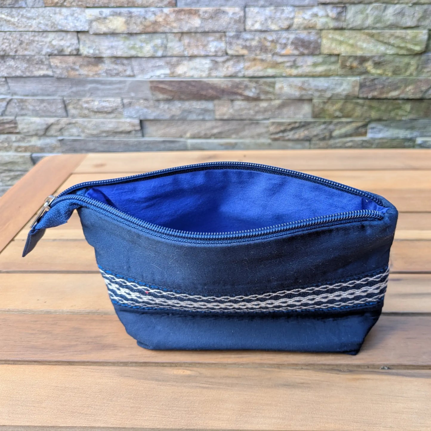 Trousse bleue zippée vue ouverte, avec doublure bleue et bande tissée décorative extérieure.