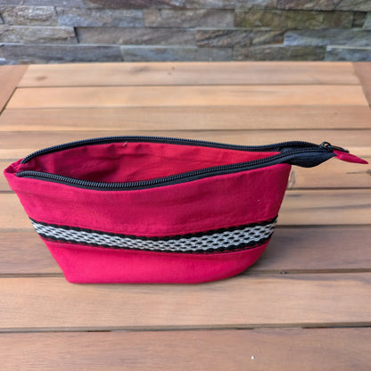 Trousse rouge zippée vue ouverte, avec doublure rouge et bande tissée décorative sur la face extérieure.