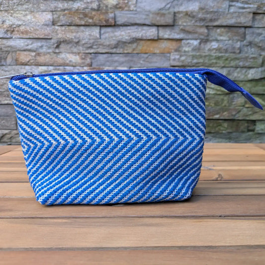 Trousse de toilette artisanale bleu et blanc, tissée main en chevrons avec fermeture zippée bleue.