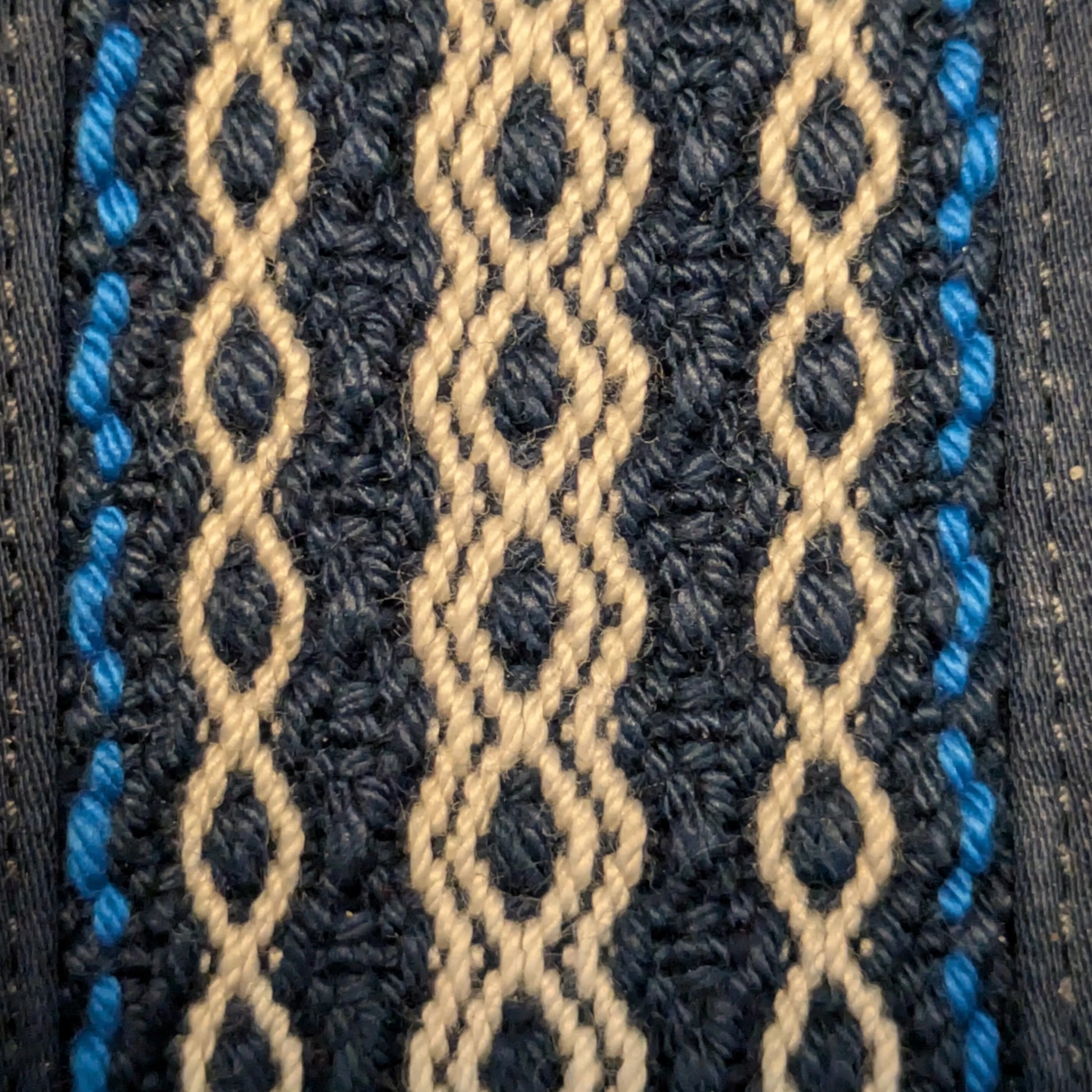 Détail de la bande tissée manuellement, fils bleus, beiges et blancs en motifs géométriques.