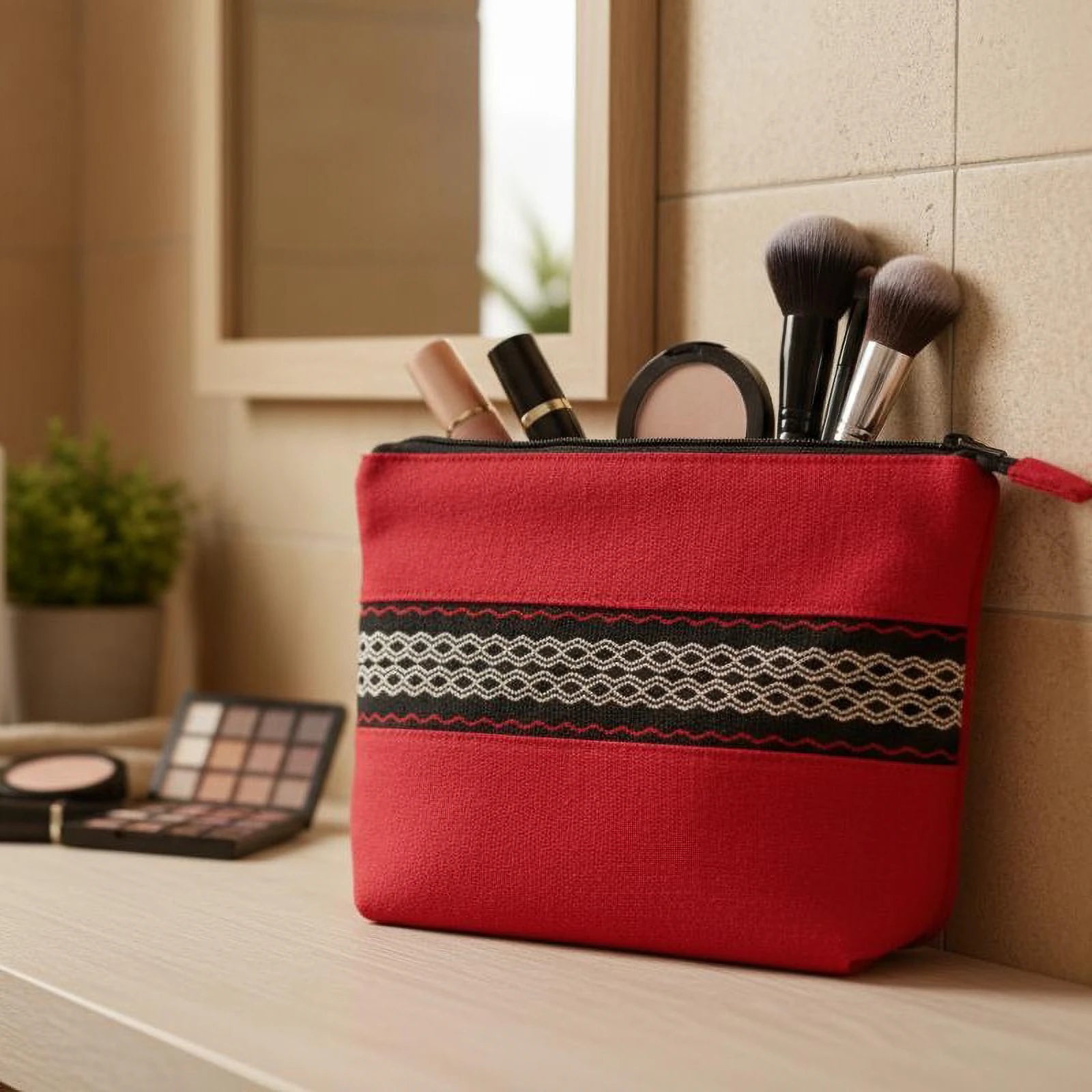 Trousse de toilette artisanale rouge, couture manuelle et bande tissée traditionnelle, ambiance naturelle.