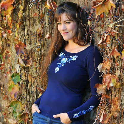 T-shirt bleu aux manches longues pour femmes avec des broderies hongroises traditionnelles Matyó, sur la poitrine et les manches. Vue légèrement de biais.