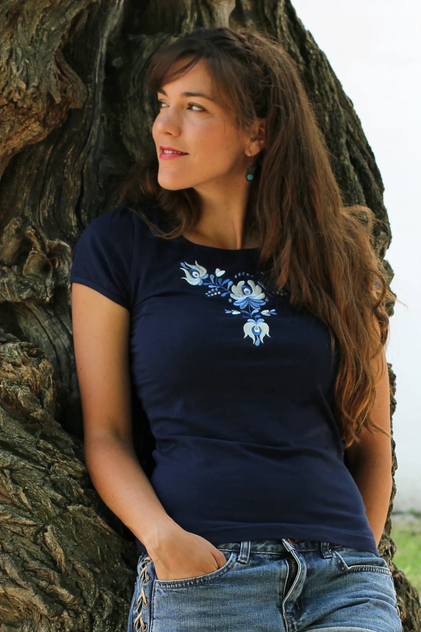 T-shirt bleu à manches courtes pour femmes. Il est brodé avec des fleurs Matyó dans des tons clairs de bleu et de blanc offrant un ensemble esthétique.