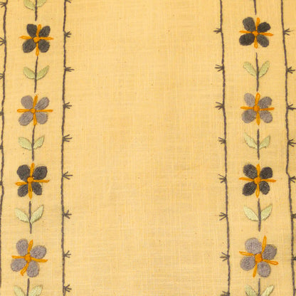 Gros plan sur une broderie en lin aux fleurettes répétées. Les motifs sont alignés verticalement. Un travail artisanal brodé main.